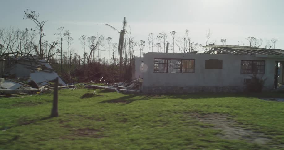 Homes and trees damaged and destroyed by tornado with tents set up in the yard