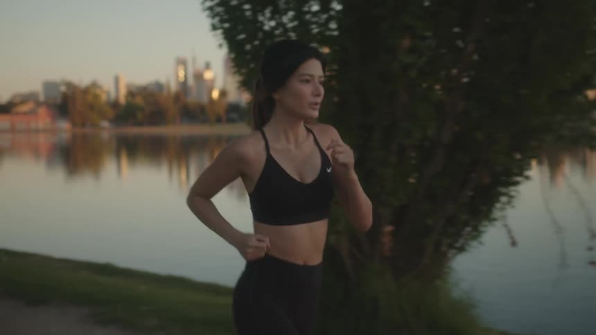 Young woman jogging along lake shoreline in the city with skyline in the background