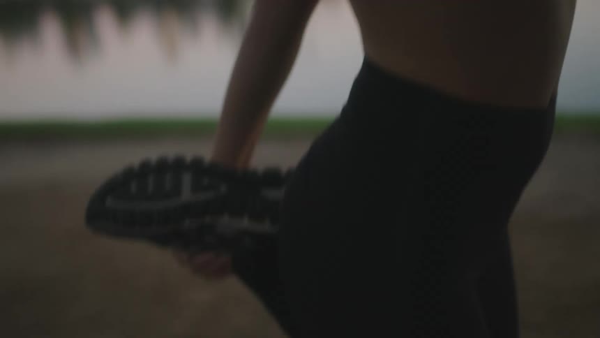 A woman is stretching near the water