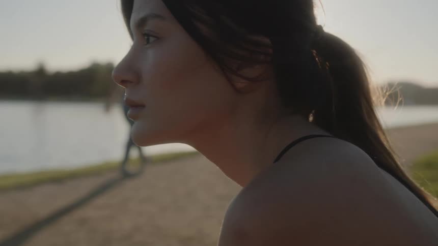 A woman is sitting outdoors by the beach at dusk