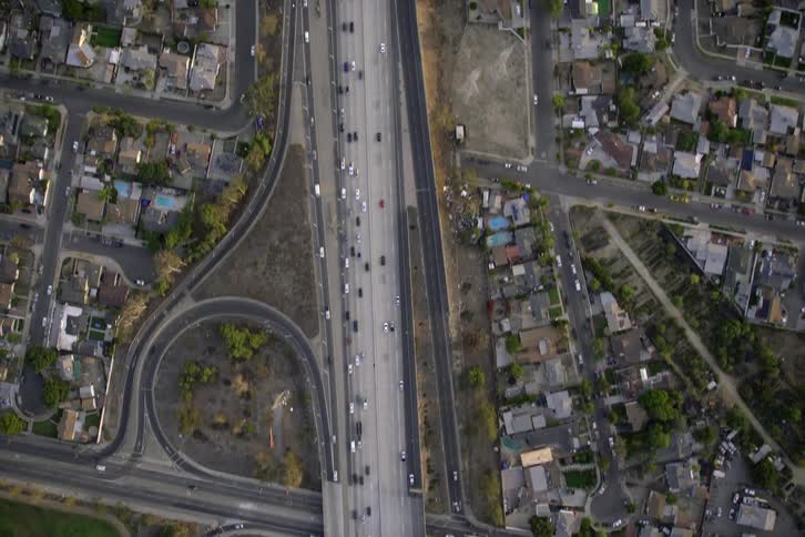 An aerial view of cars driving past neighborhoods