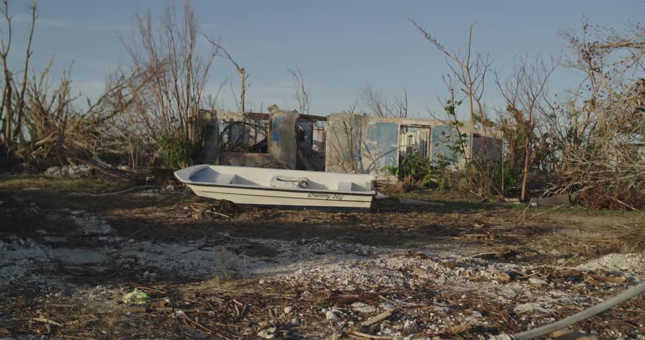 A boat sitting in front of an abandoned house