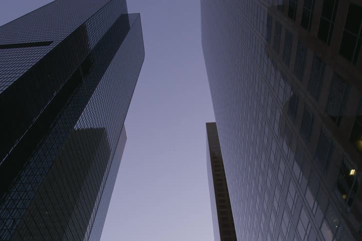 City skyscrapers seen from moving vehicle on highway at dusk