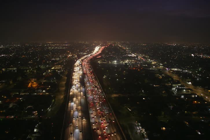 Cars are driving on a highway in a city at night