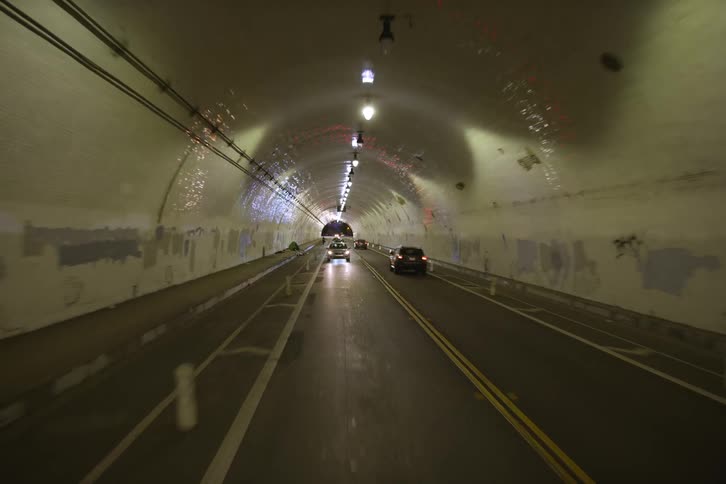 Traffic travels along a road through a long tunnel at night