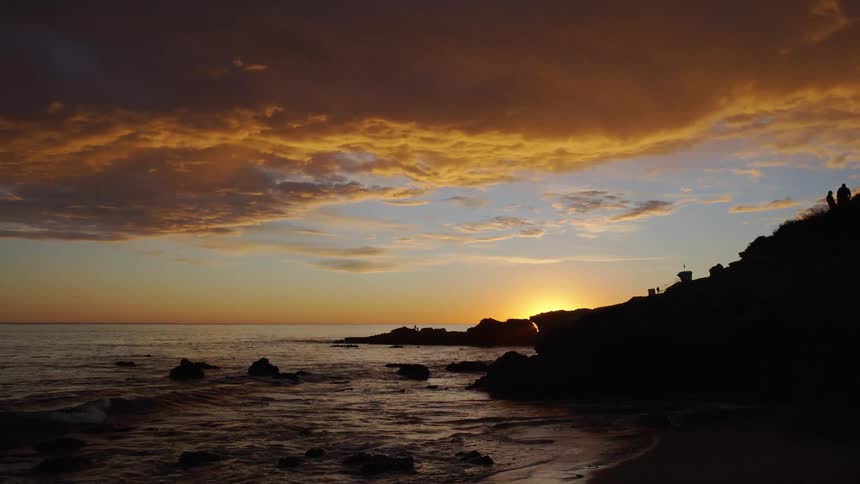 A rocky coastline under a cloudy sky at sunset