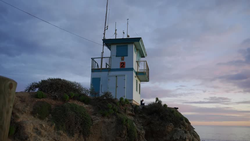 A lighthouse is near a body of water at dusk
