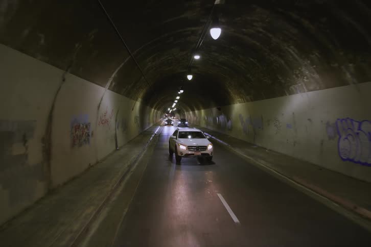 Cars are driving under a tunnel at night