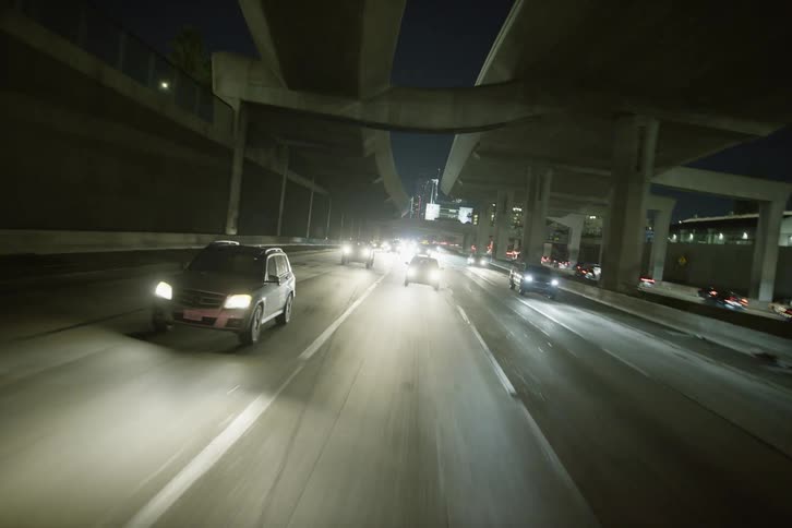 Traffic travels along a freeway at night