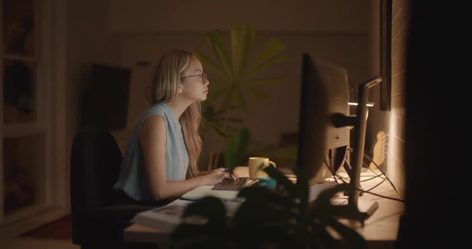 A woman is typing on a computer in a room