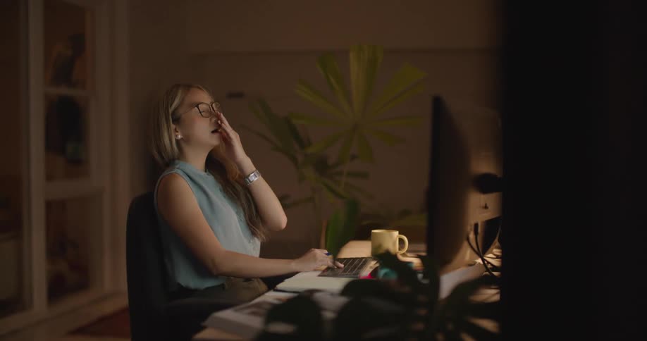 Female tired and yawning working late at night in the office