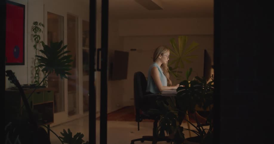 A woman is typing on a computer in her house