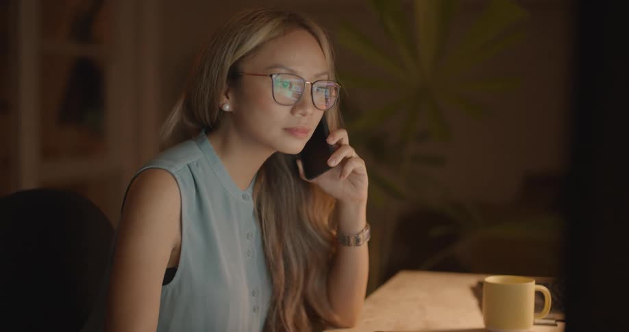 A woman talks on a cell phone at her desk