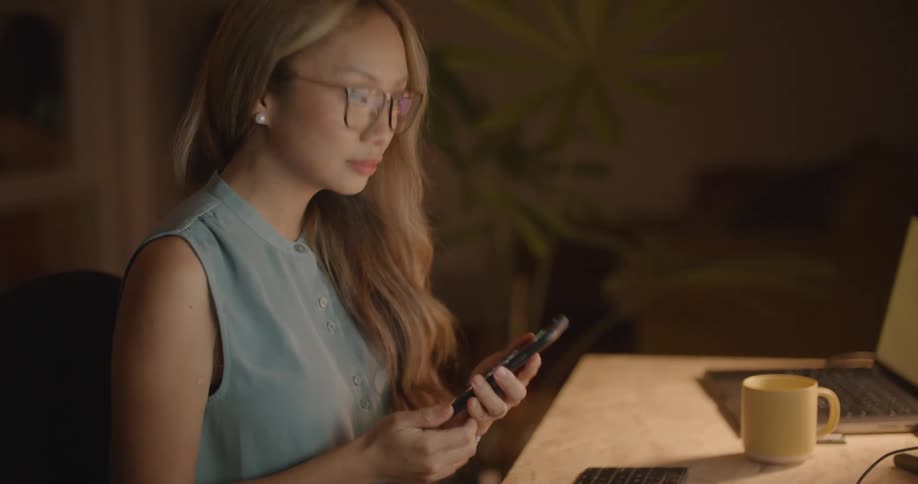 A woman is sitting at a computer desk and talking on the phone