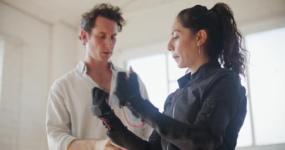 A man shows a woman wearing virtual reality equipment how to move her hands