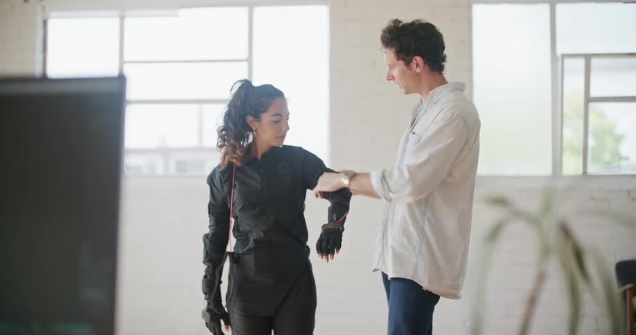 A man helps a colleague put on a motion capture suit