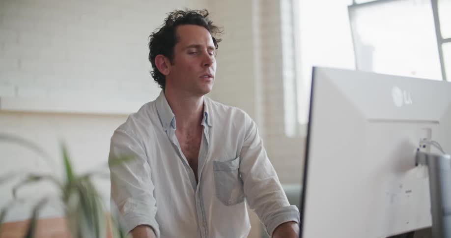 A man motions with his wrist and hand in the air while sitting at his desk