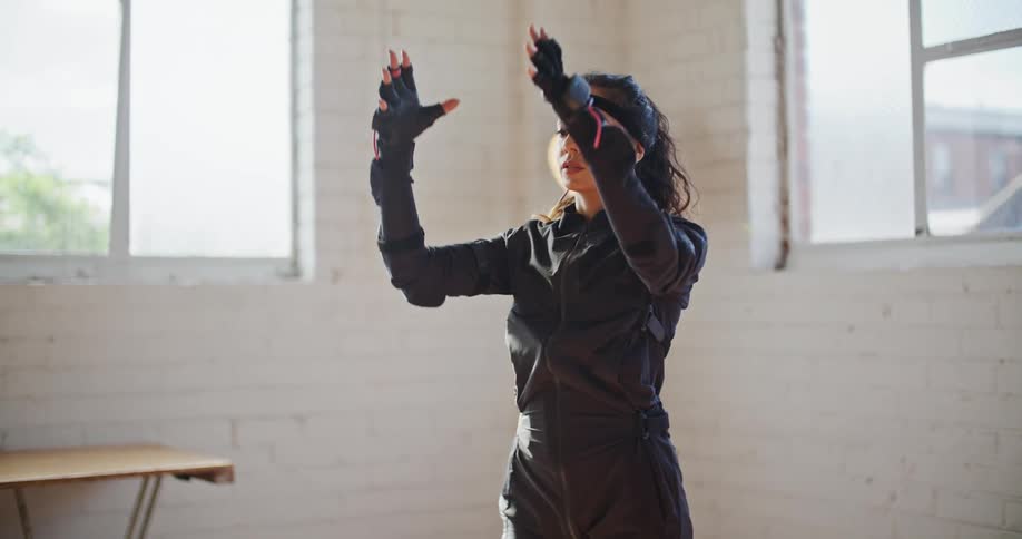 A woman is stretching in a room near a window
