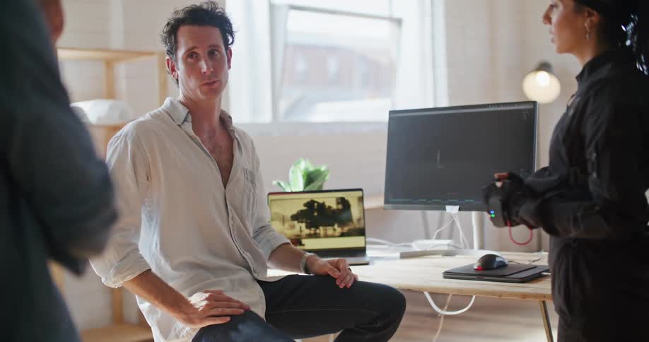 Three colleagues chat around a desk in the office