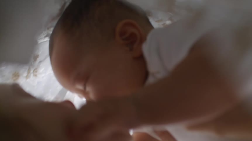 Mother holding her baby under the blanket and playing with it