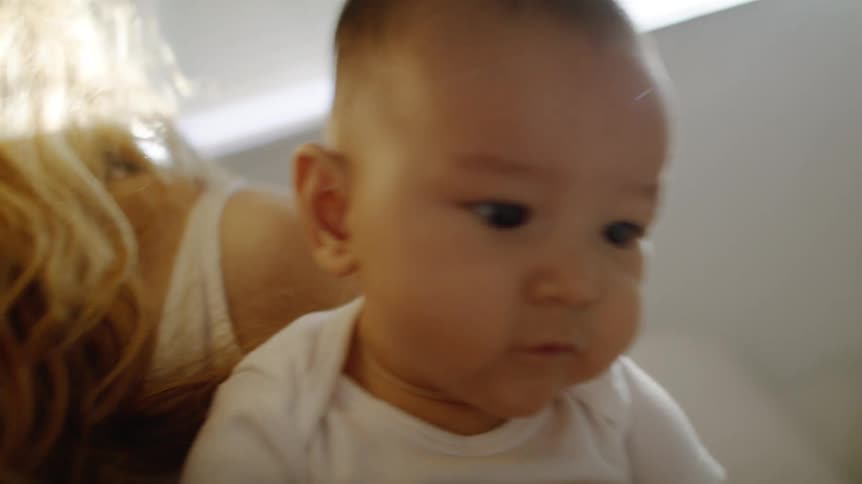 A woman at home holds her young baby in her arms