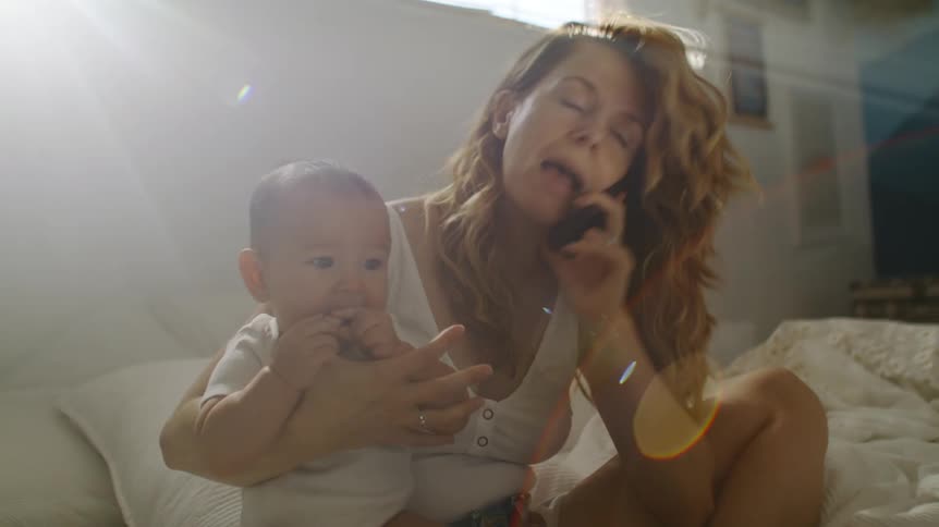 A woman talks on her cell phone while holding her baby