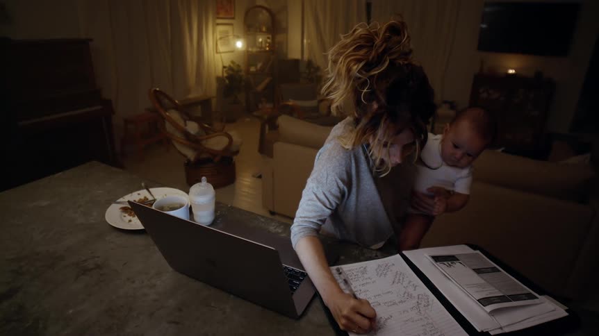 Mother multitasking holding baby working from home