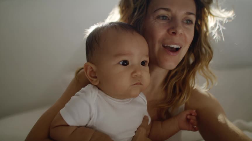 A mother holds her son while talking on the cell phone