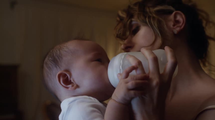 A mother feeds her crying baby formula