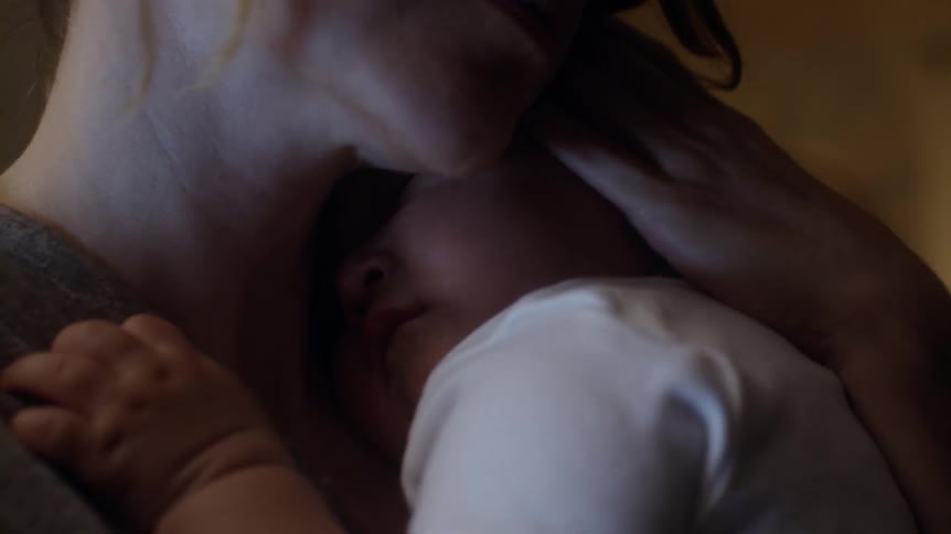 A woman rocks her baby to sleep in her arms