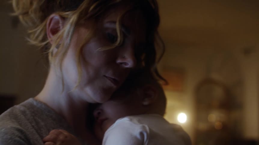 Mother holding and rocking her baby inside the house