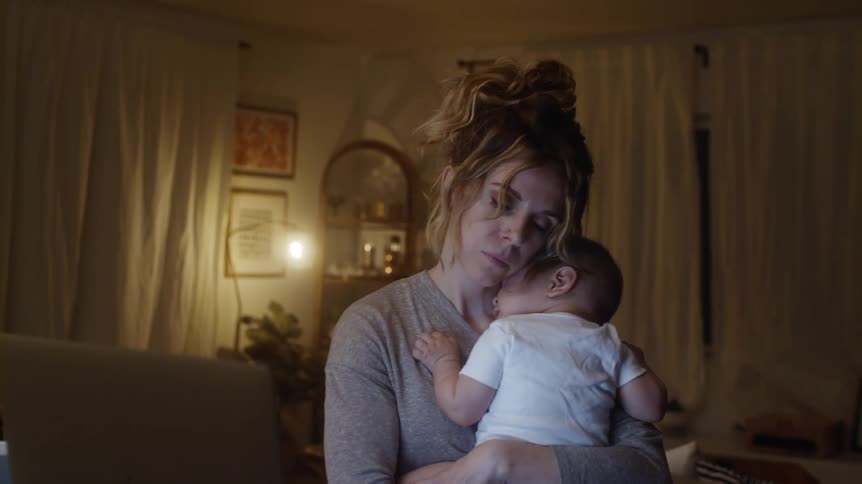 A mother cradles her baby at night