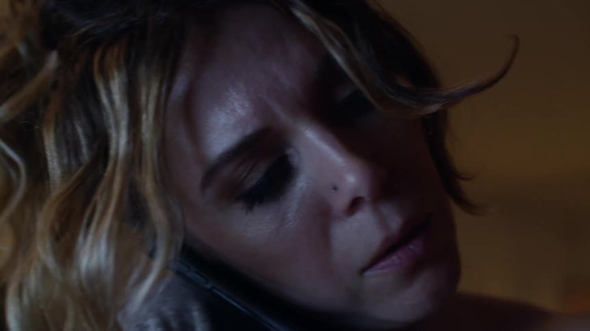 Worried mother holding her son and checking his temperature for fever while she talks to the phone