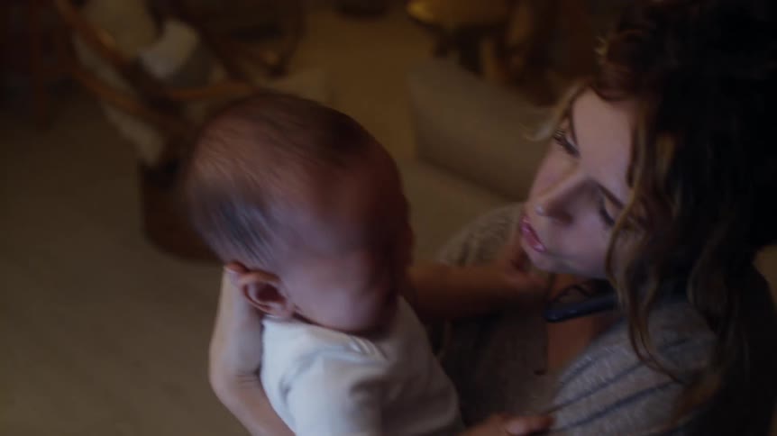 A mother cradles a baby with a fever and answers her cell phone