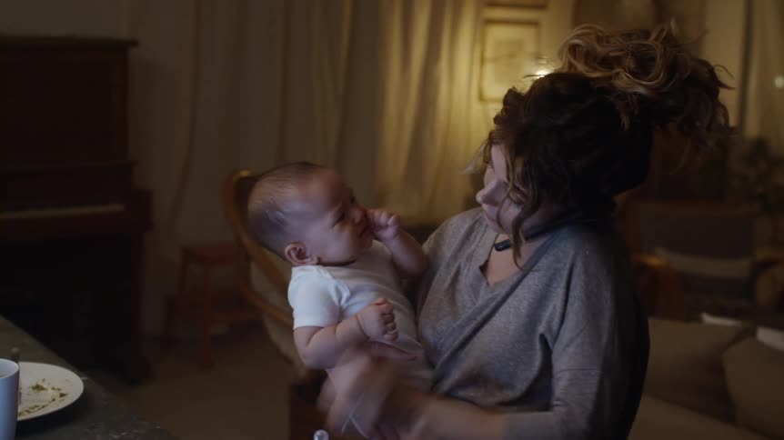 A woman rocks her infant son while talking on the phone