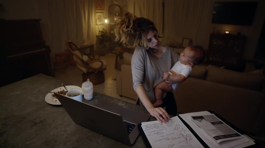 A woman cradles her baby while writing something down