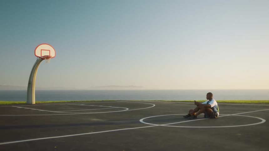 A man is sitting on an empty basketball court