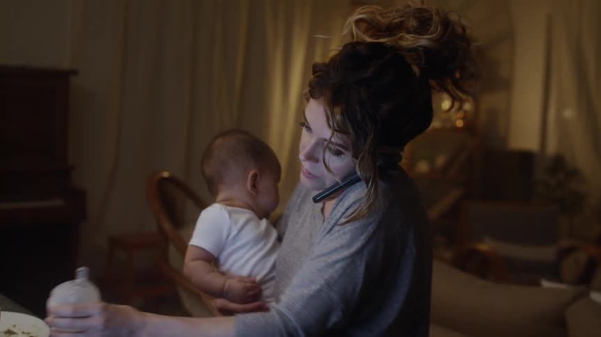A mother rocks her son while talking on the phone