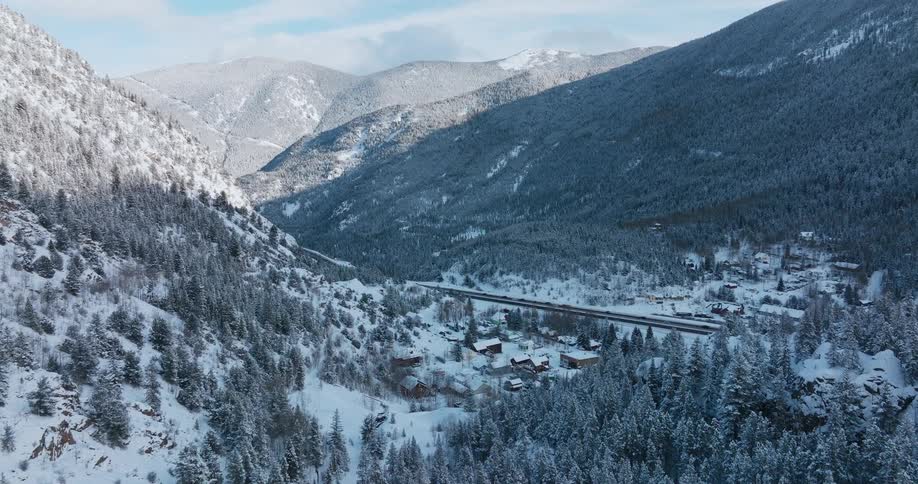 A road that passes through a snow covered mountain range is filled with numerous moving vehicles