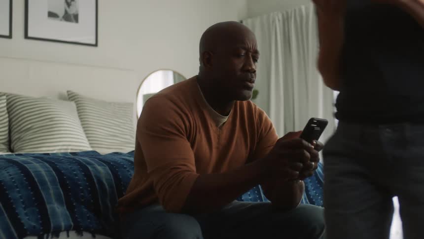 Two people are using their cell phones and walk out of the room