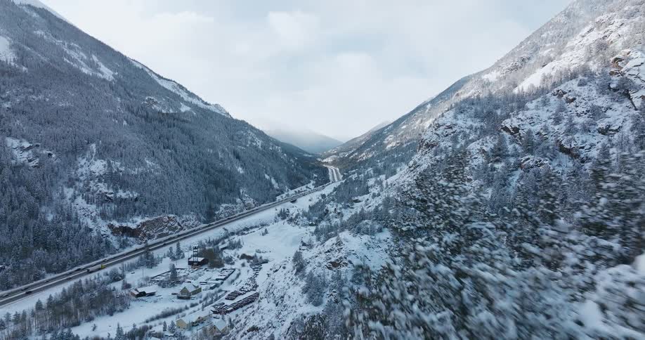 Cars are driving on a road near snowy mountains