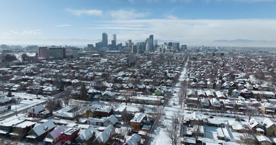 Aerial of snow covered urban neighborhood with skyline in the distance