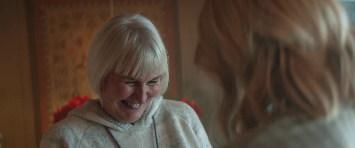 Old woman talking and laughing to another woman inside the house