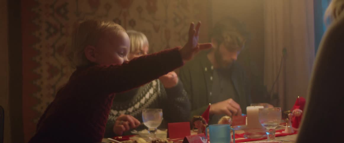A toddler reaches out to his mother as the family sits down for dinner