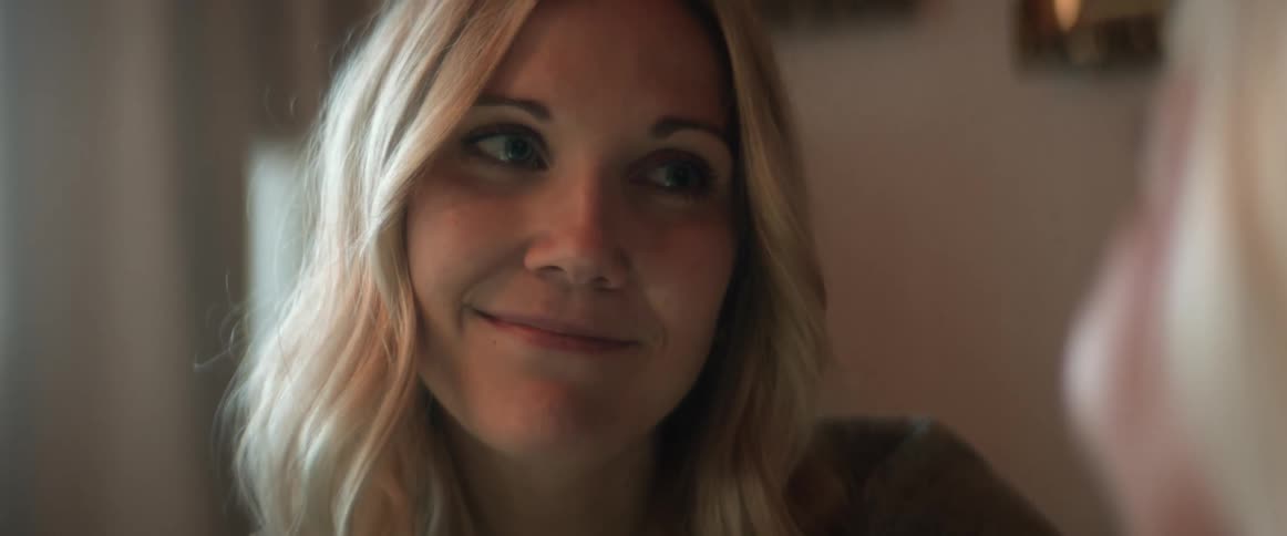 A woman is sitting indoors and smiling