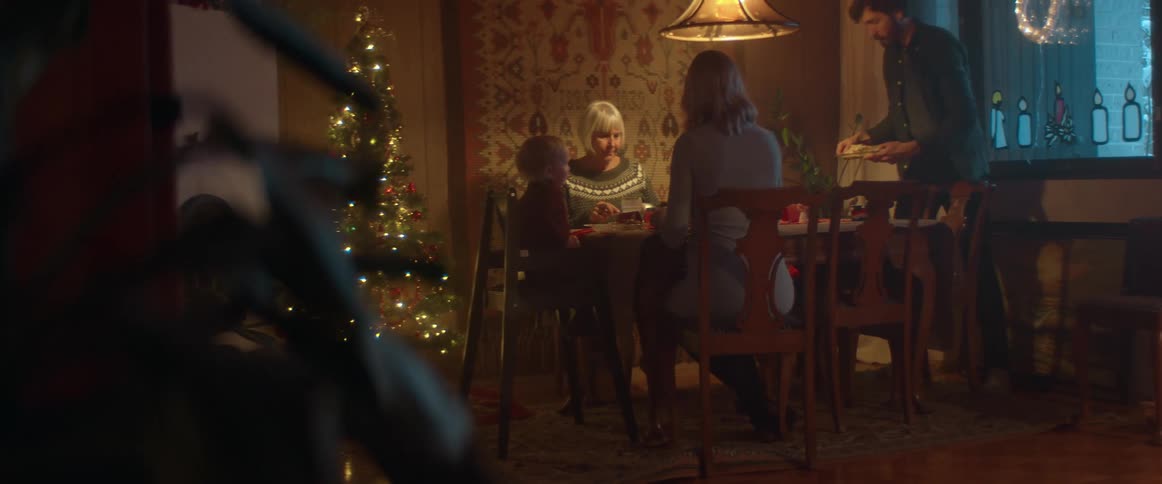 Family sitting at the table enjoying the christmas dinner when a man arrives and joins them