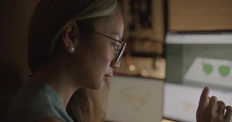 A woman examines a pair of sunglasses at her desk
