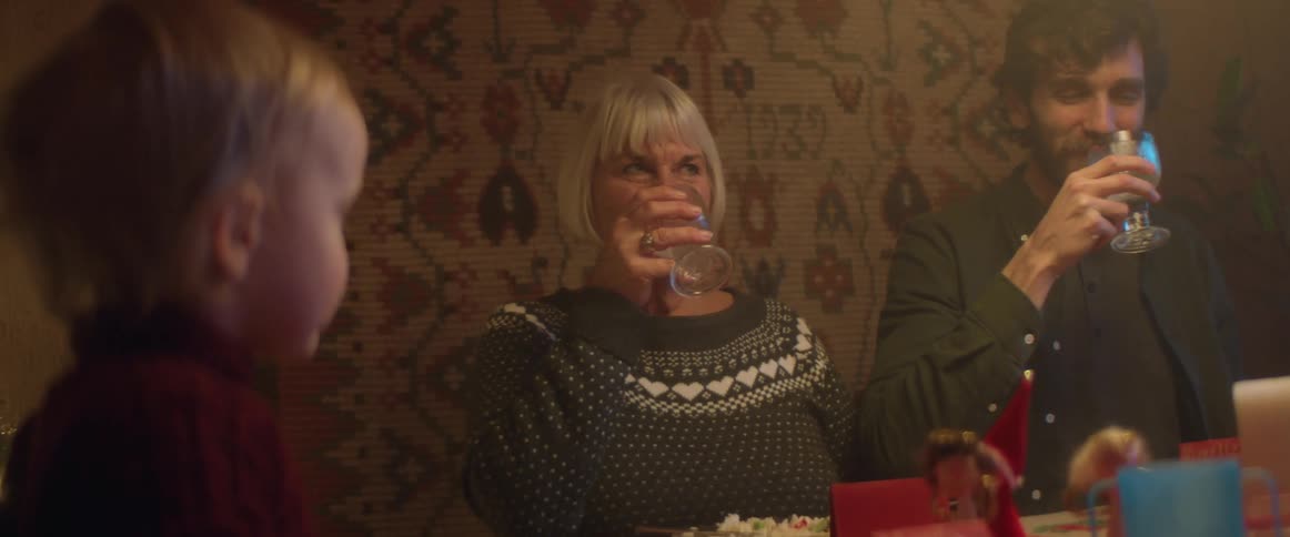 Family toasting and drinking at the christmas dinner table with a baby watching it