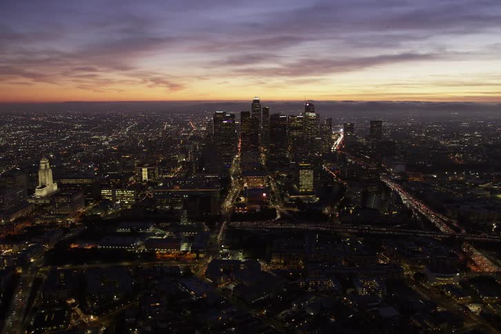 A big city is lit up with a lot of traffic on the streets under a colorful sky