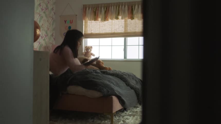 A child walks out of the bedroom with a tablet